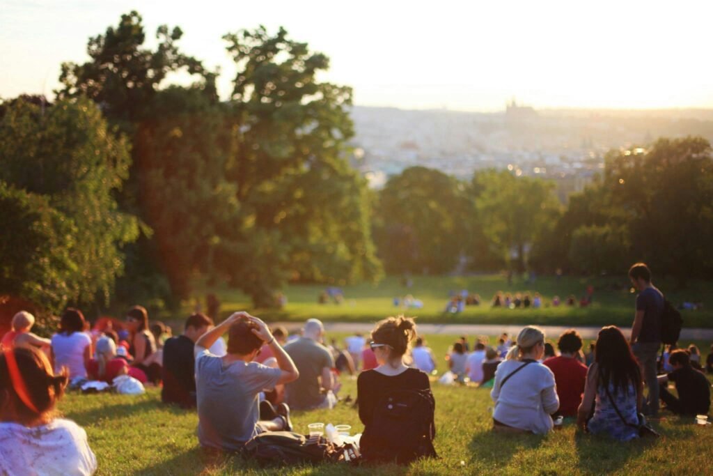 Pessoas aproveitam o pôr do sol em um parque, curtindo momentos de lazer ao ar livre em meio à natureza.
