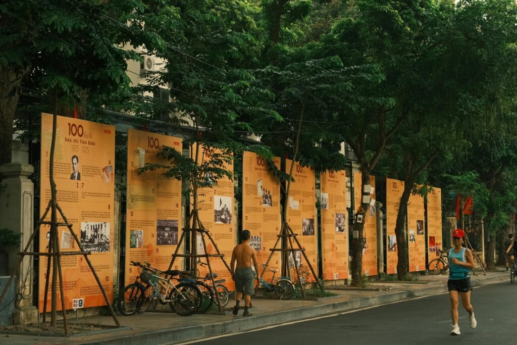 Pessoas praticam atividades físicas ao lado de murais históricos em uma rua arborizada, unindo saúde e cultura.
